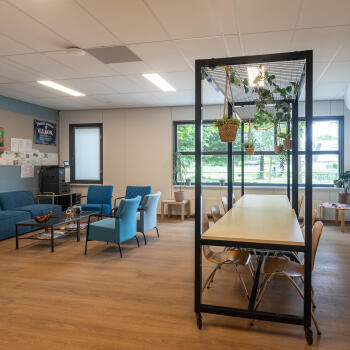 zithoek met salontafel en fauteuils en vergadertafels met stoelen