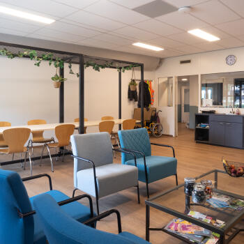 zithoek met salontafel en fauteuils en vergadertafels met stoelen, aanrechtblad