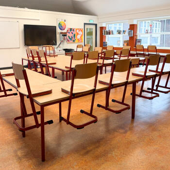 leslokaal met schoolmeubilair en stoelen op tafel