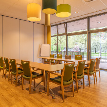 vergaderruimte met grote raampartij en voorzien van tafelsopstelling in U-vorm met felgroene stoelen