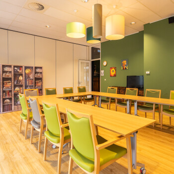 vergaderruimte  voorzien van tafelsopstelling in U-vorm met felgroene stoelen met een groene wand