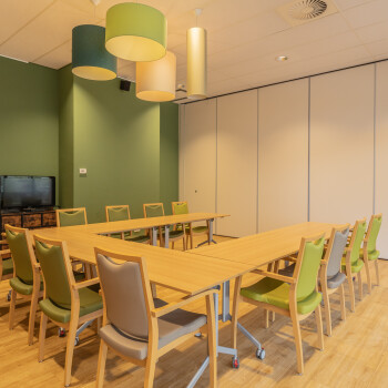 vergaderruimte  voorzien van tafelsopstelling in U-vorm met felgroene stoelen met een groene wand