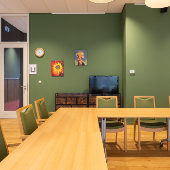 deel van de U-tafelopstelling enkele stoelen en groene wand
