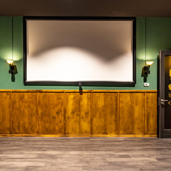 bioscoopscherm met groene wand en aan beide zijden een wandlampje