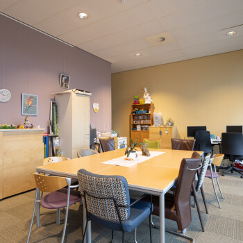 tafel met stoelen, lila wand links, lichtgeel andere wand