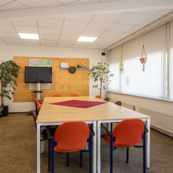 tafels met stoeen een tv en rechts een raampartij