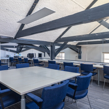 balken aan plafond, witte tafel met blauwe stoelen