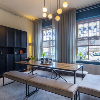 wandkast, tafel met lage zitbanken en raampartij