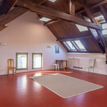 vrije ruimte met vloerkleed en enkele stoelen tegen de wand