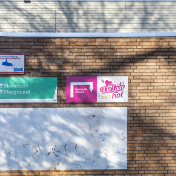 bewegwijzeringsbord op het pand met de tekst: ingang om de hoek