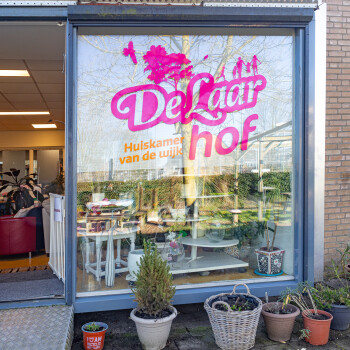 deur naar woonkamer en bestickerde pui met logo van De Laarhof