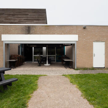 buitenfoto van het gebouw met terras, gras en picknicktafels