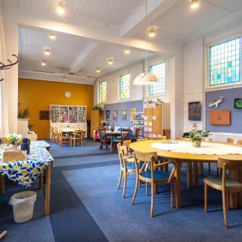 zaal met ronde tafel met stoelen en lange tafel met stoelen