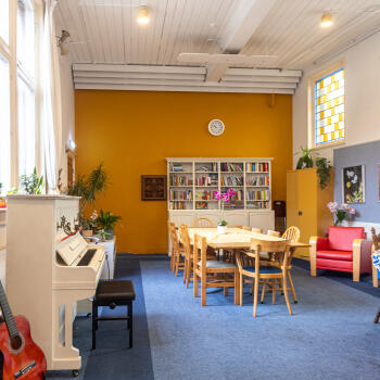 boekenkast tegen de wand, tafels en stoelen, piano