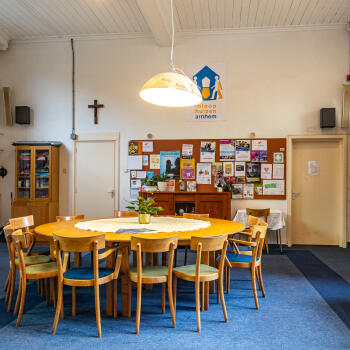 wandkast tegen de wand, wandpaneel met flyers/posters en ronde tafel met stoelen
