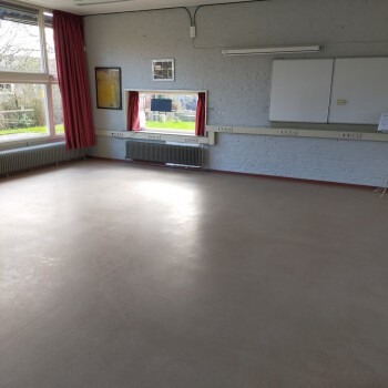 lege zaal met op de muur een whiteboard en een open raam
