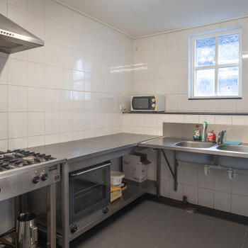 keuken met RVS-werkblad en spoelbak en fornuis
