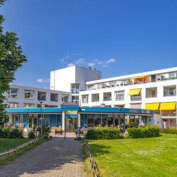 voorzijde van het gebouw, blauw naambord, gras en blauwe lucht