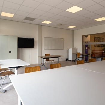 tafels met stoelen, kasten, tv, whiteboard