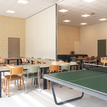 2 ruimtes met deel van scheidingswand, tafels, stoelen, tafeltennistafel