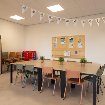 tafel, stoelen, prikbord aan de wand